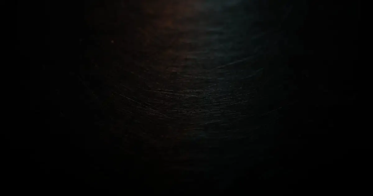 Brushed dark steel catching warm and cool light, the clear surface a professional services website gives a firm's expertise