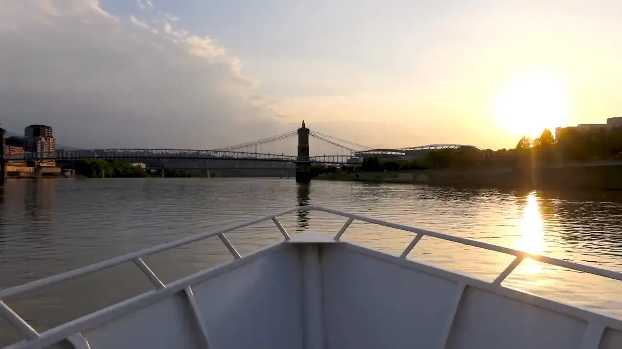 The bow of the Destiny heading toward the Roebling Suspension Bridge at sunset