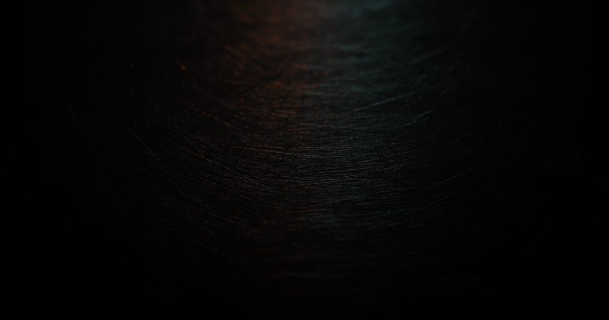 Brushed dark steel catching warm and cool light, illustrating what custom software development costs in Cincinnati
