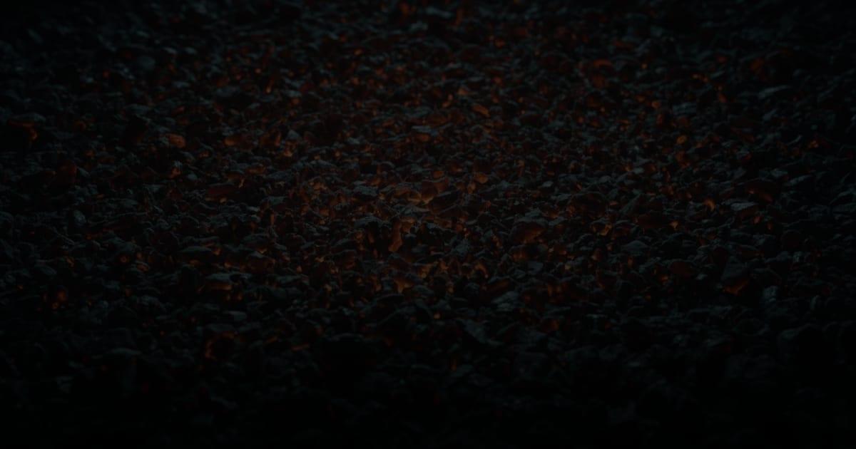 Scattered orange embers across a bed of dark forge coal
